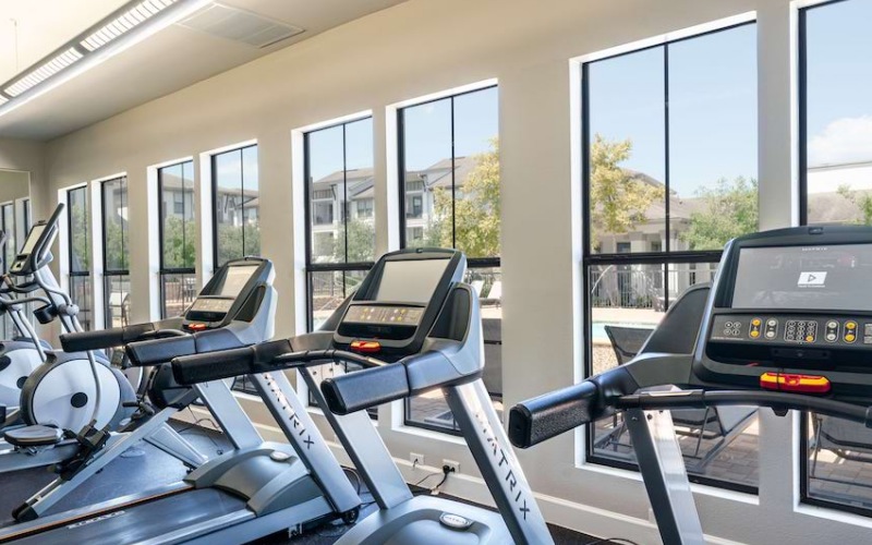 spacious fitness center with ample lighting, cardio and weight training equipment and ceiling fans